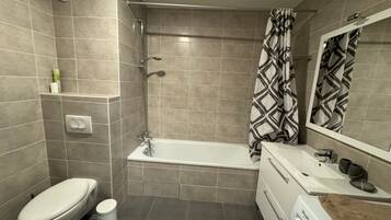 Een moderne badkamer met een bad, toilet en een wastafel met een handdoek.