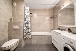 Un baño moderno con inodoro, ducha y lavadora.