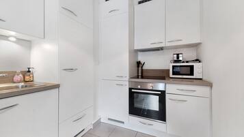 A modern kitchen with white cabinetry, a built-in oven, and a microwave.