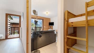 Ett rum med en våningssäng, en soffa, en tv och ett fönster med utsikt över en träveranda.