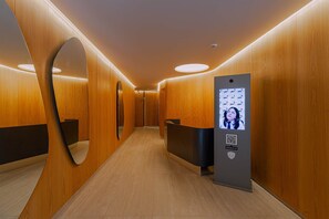 Un moderno vestíbulo de hotel con paneles de madera, una recepción y un quiosco informativo digital.