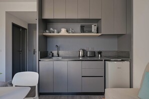 A compact kitchen with grey cabinets, a microwave, a coffee maker, and a small refrigerator. - MOT Rentals + Design SohoHaus '605' - 3 pax Full Amenities (Buenos Aires)