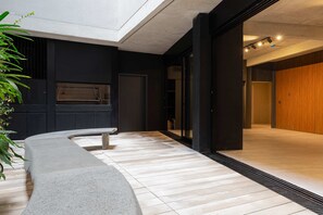 A modern interior with a concrete bench, a wooden floor, and a black wall with a door. - MOT Rentals + Design SohoHaus '605' - 3 pax Full Amenities (Buenos Aires)