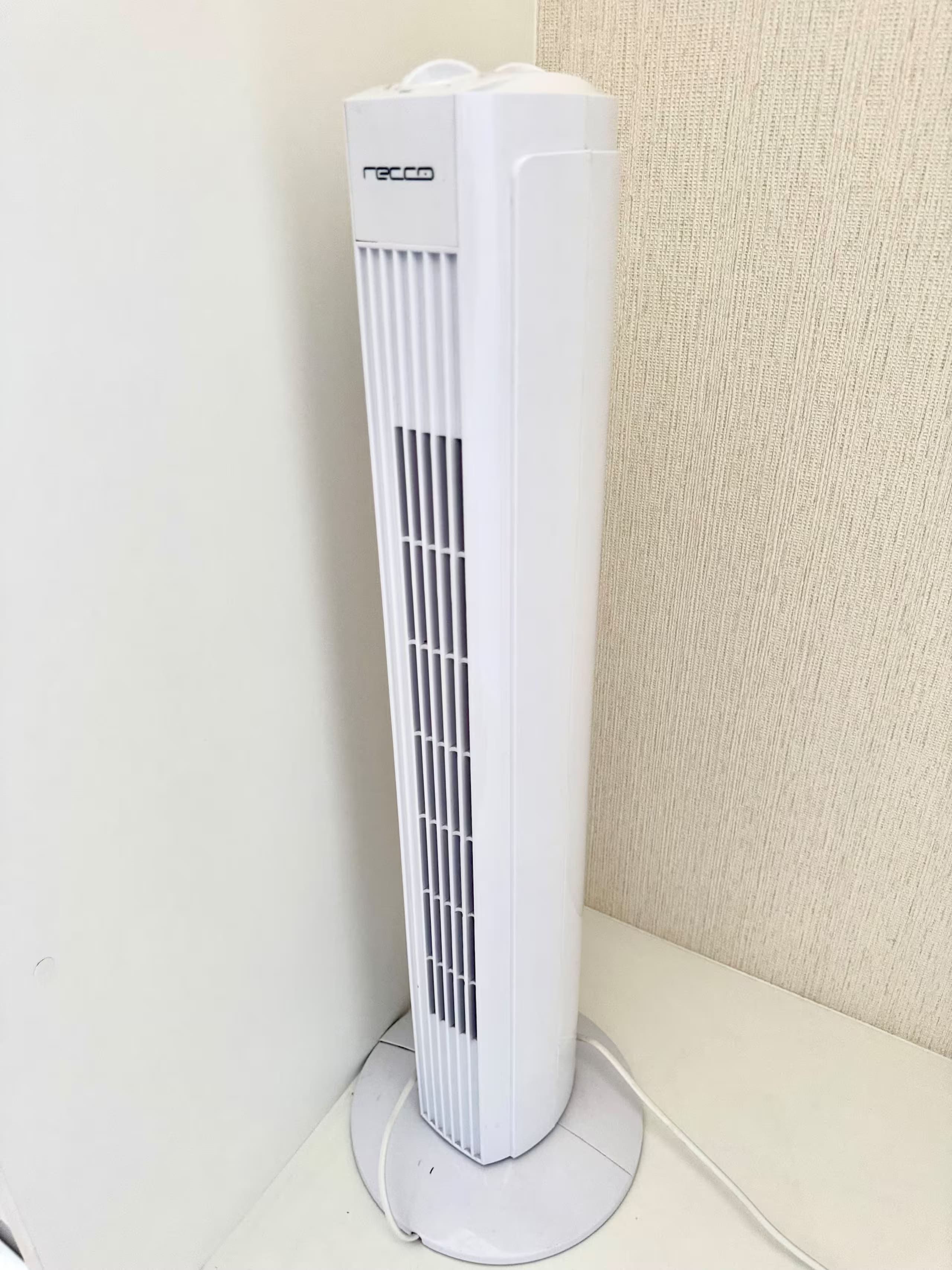 A white portable air conditioner with a vent on the front, standing on a white base.