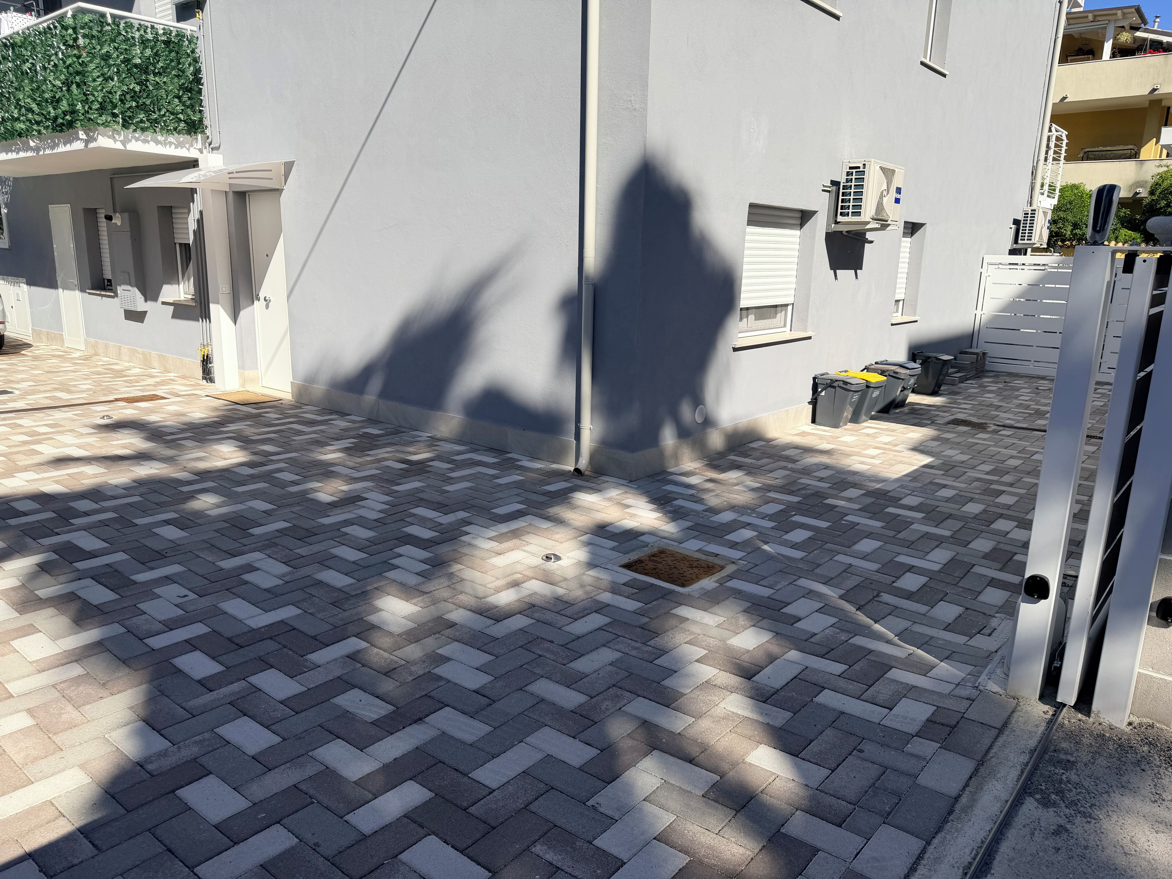 Un cortile lastricato con un muro grigio, una porta e una finestra.