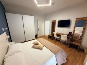 Una habitación de hotel con una cama, un escritorio, una silla, un televisor y un armario.