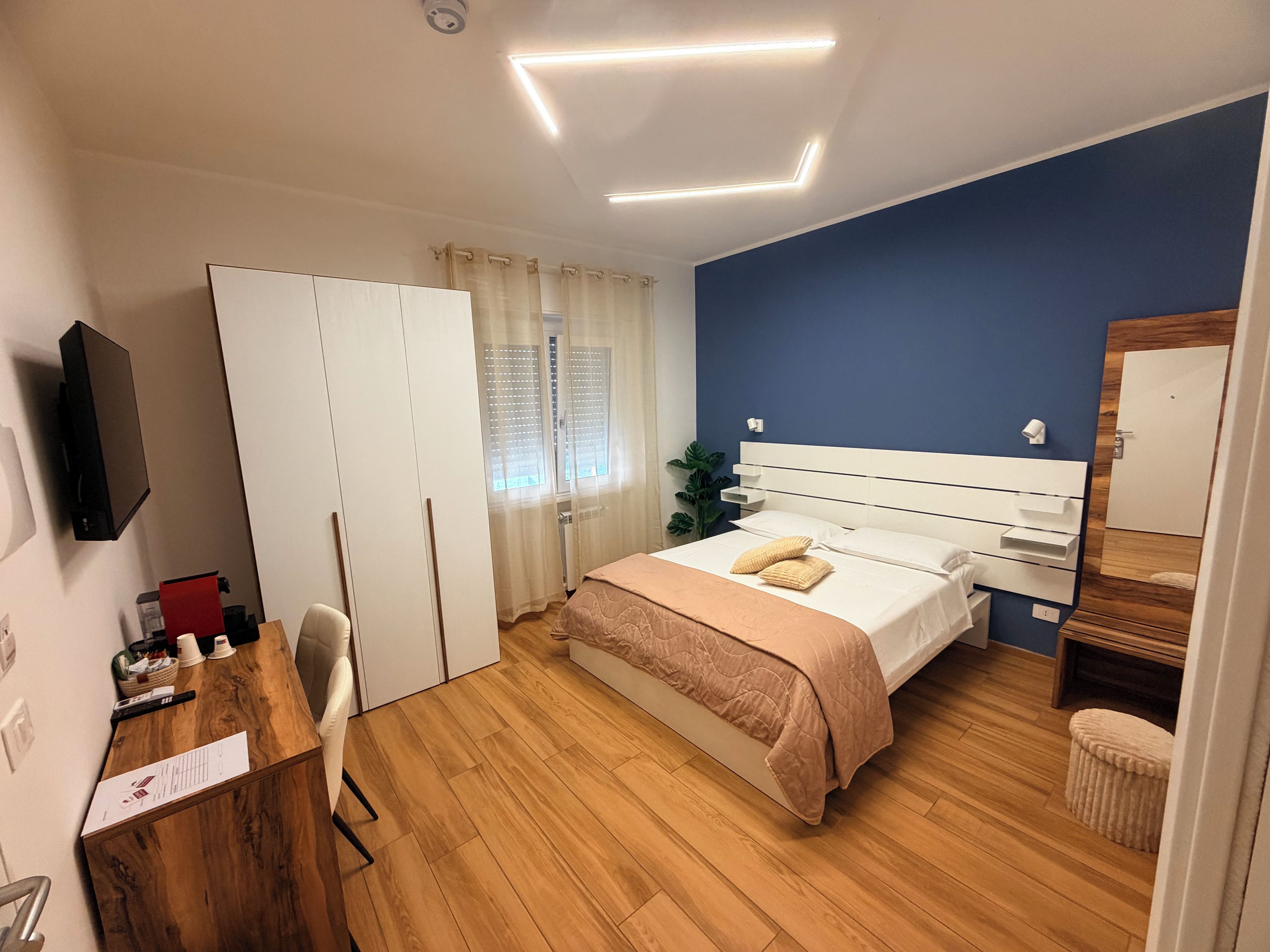 Un dormitorio con cama, escritorio, silla, armario y espejo.