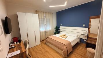 Un dormitorio con cama, escritorio, silla, armario y espejo.
