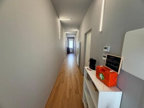 A hallway with a wooden floor, a reception desk with a sign indicating WiFi availability, and a wall-mounted thermostat. - Palazzo del toro 2 (Montesilvano)