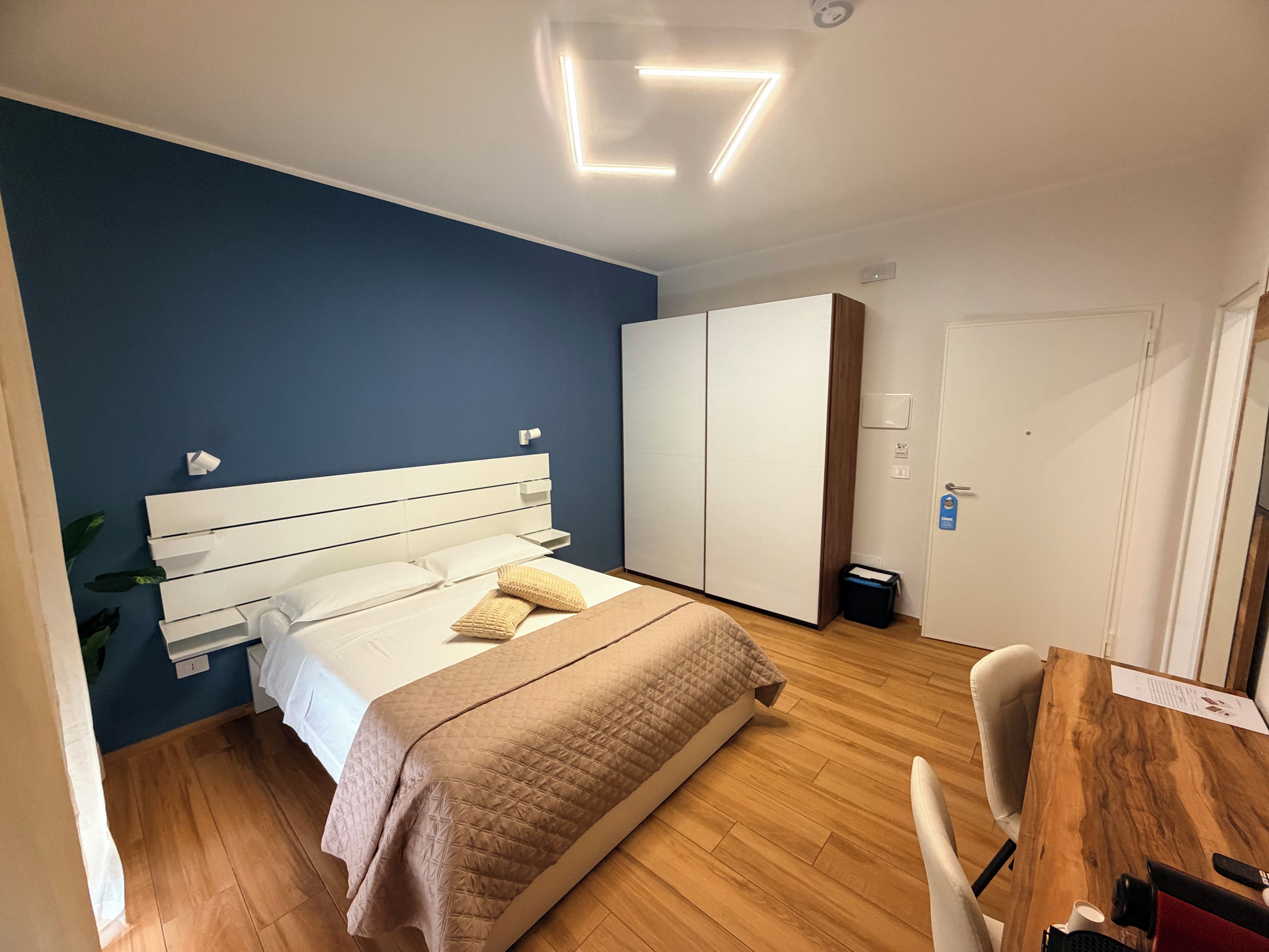 A modern bedroom with a bed, a desk, and a wardrobe.