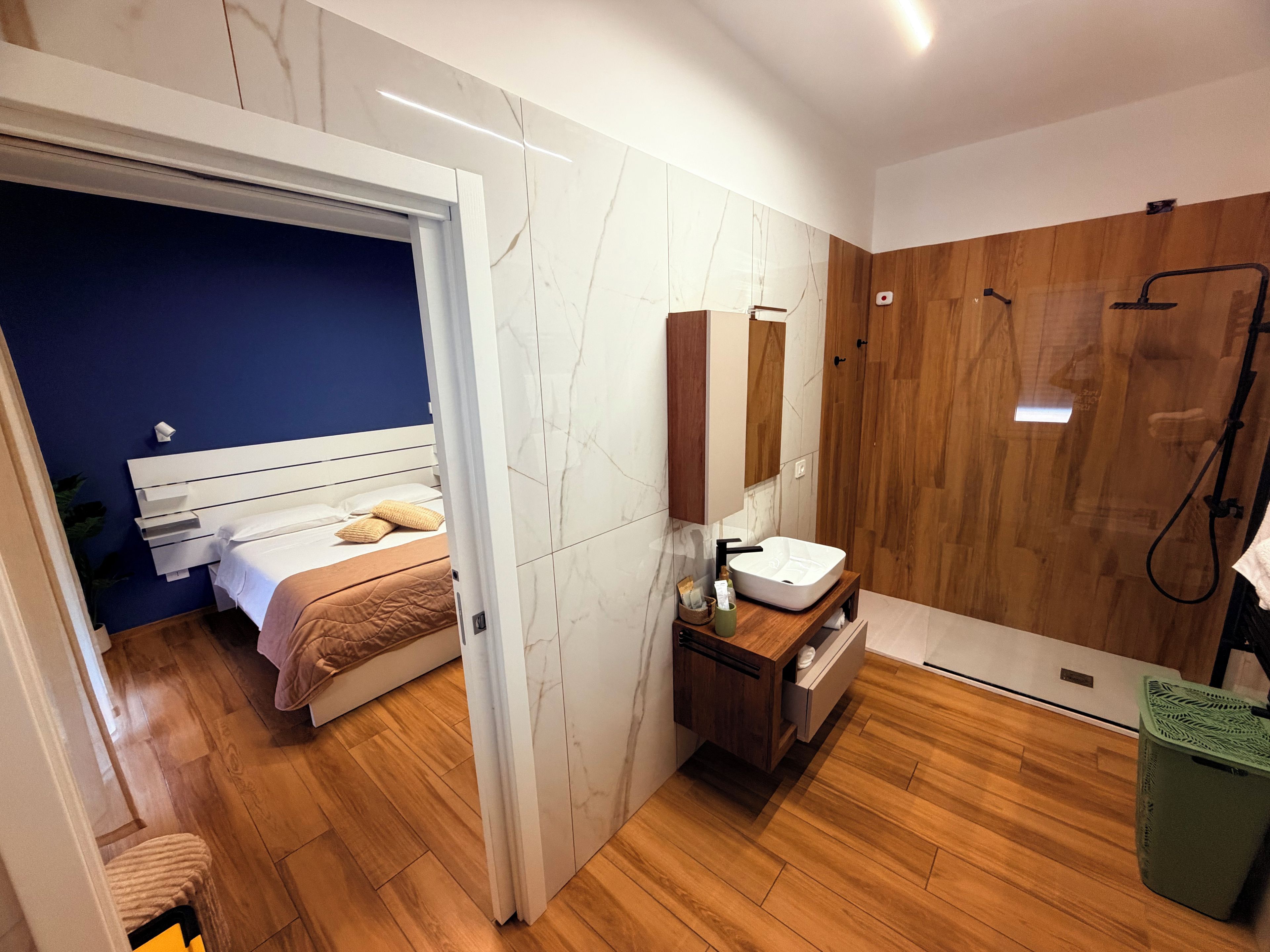 Une salle de bain moderne avec un meuble-lavabo en bois, un grand miroir et un espace douche.