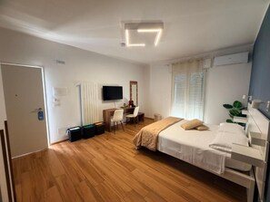 A bedroom with a bed, a desk, a chair, a television, and a window with blinds. - Palazzo del toro 2 (Montesilvano)