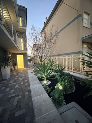 A courtyard with a paved walkway, a small water feature, and potted plants. - Palazzo del toro 2 (Montesilvano)