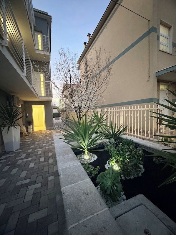 A courtyard with a paved walkway, a small water feature, and potted plants.