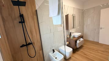 A modern bathroom with a wooden shower enclosure, a white sink, and a marble-tiled wall.