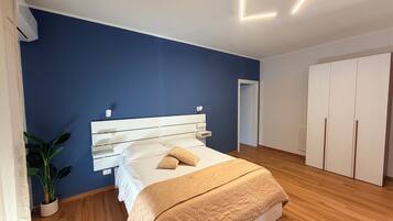 Une chambre à coucher comprenant un lit, une armoire, une plante en pot et un luminaire fixé au plafond.