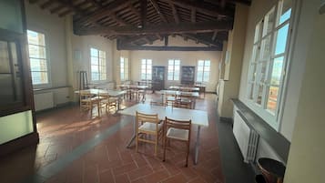 Un'ampia stanza con soffitto alto, grandi finestre e pavimento piastrellato.