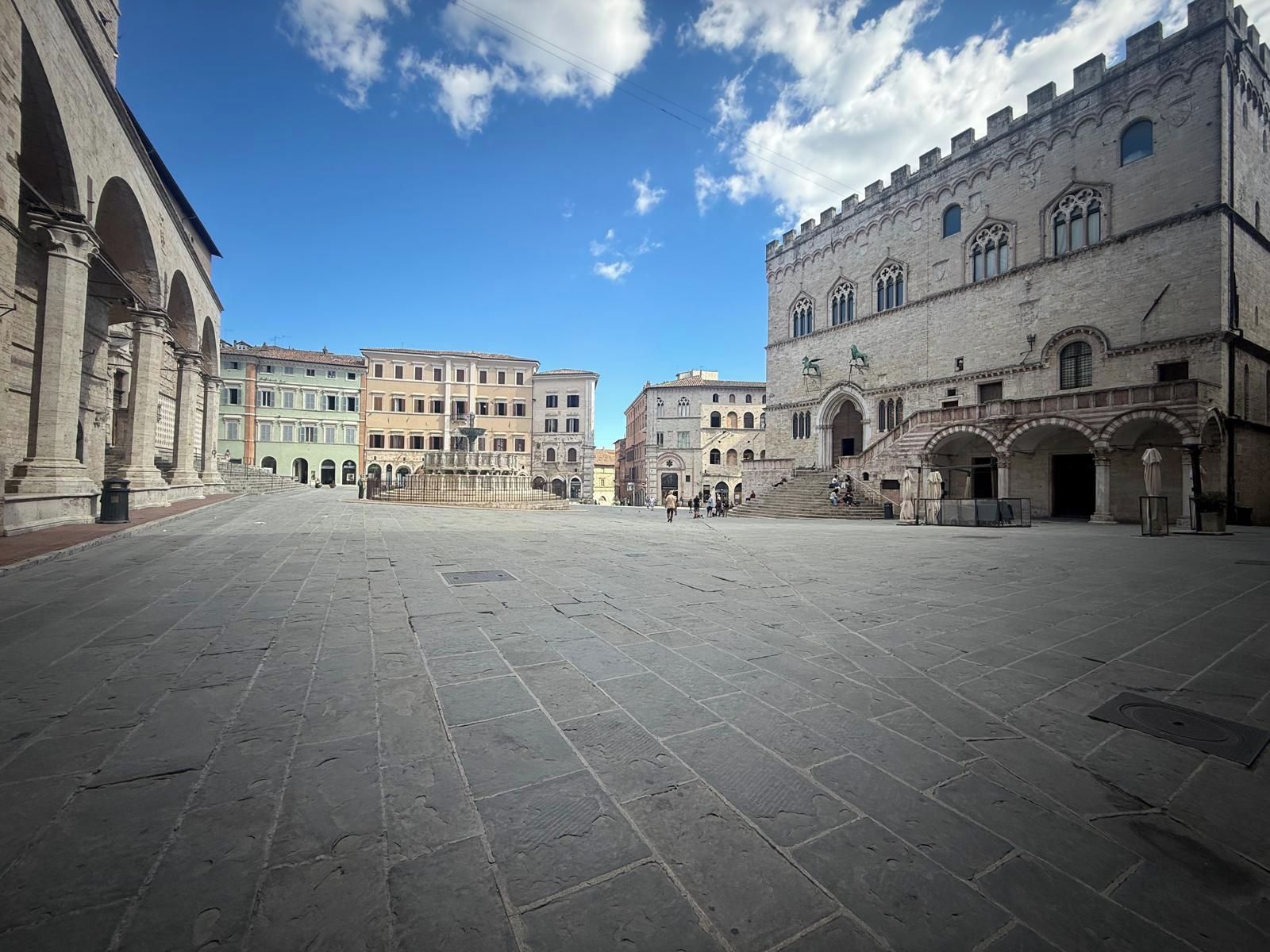 Un'ampia piazza circondata da edifici storici, tra cui spicca un edificio con finestre ad arco e statue.