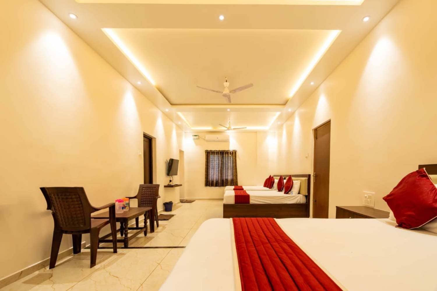 A hotel room with a bed, a desk, a chair, a television, and a ceiling fan.