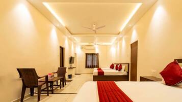 A hotel room with a bed, a desk, a chair, a television, and a ceiling fan.