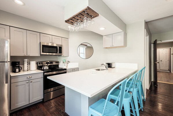 A modern kitchen with stainless steel appliances, a central island with bar stools, and a wooden ceiling beam. - Historic Old Town condo with 3 bedrooms, 3 baths, sleeps 10. (Park City)