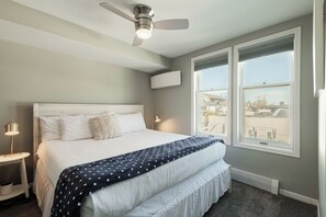 Ein Hotelzimmer mit einem Bett, einem Deckenventilator, einem Fenster mit Jalousien und einem Nachttisch mit einer Lampe.