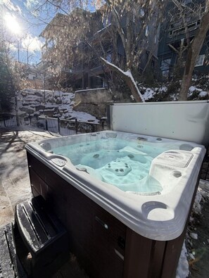 Ein Whirlpool mit Bedienfeld, umgeben von einer Steinmauer und Bäumen.
