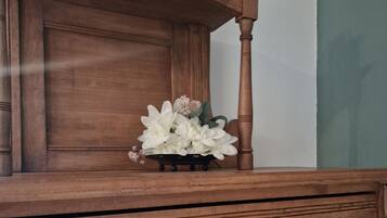 En byrå i trä med en hjärtformad dekoration och en vas med blommor ovanpå.