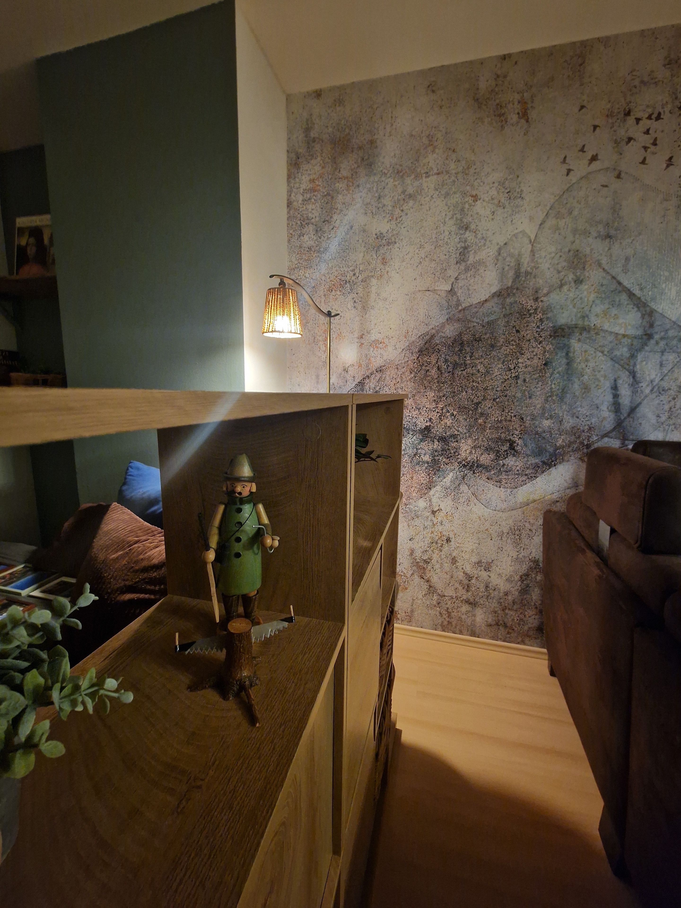 Une chambre avec un lit superposé, une petite table en bois sur laquelle est posée une figurine, une lampe et un mur à la texture particulière.