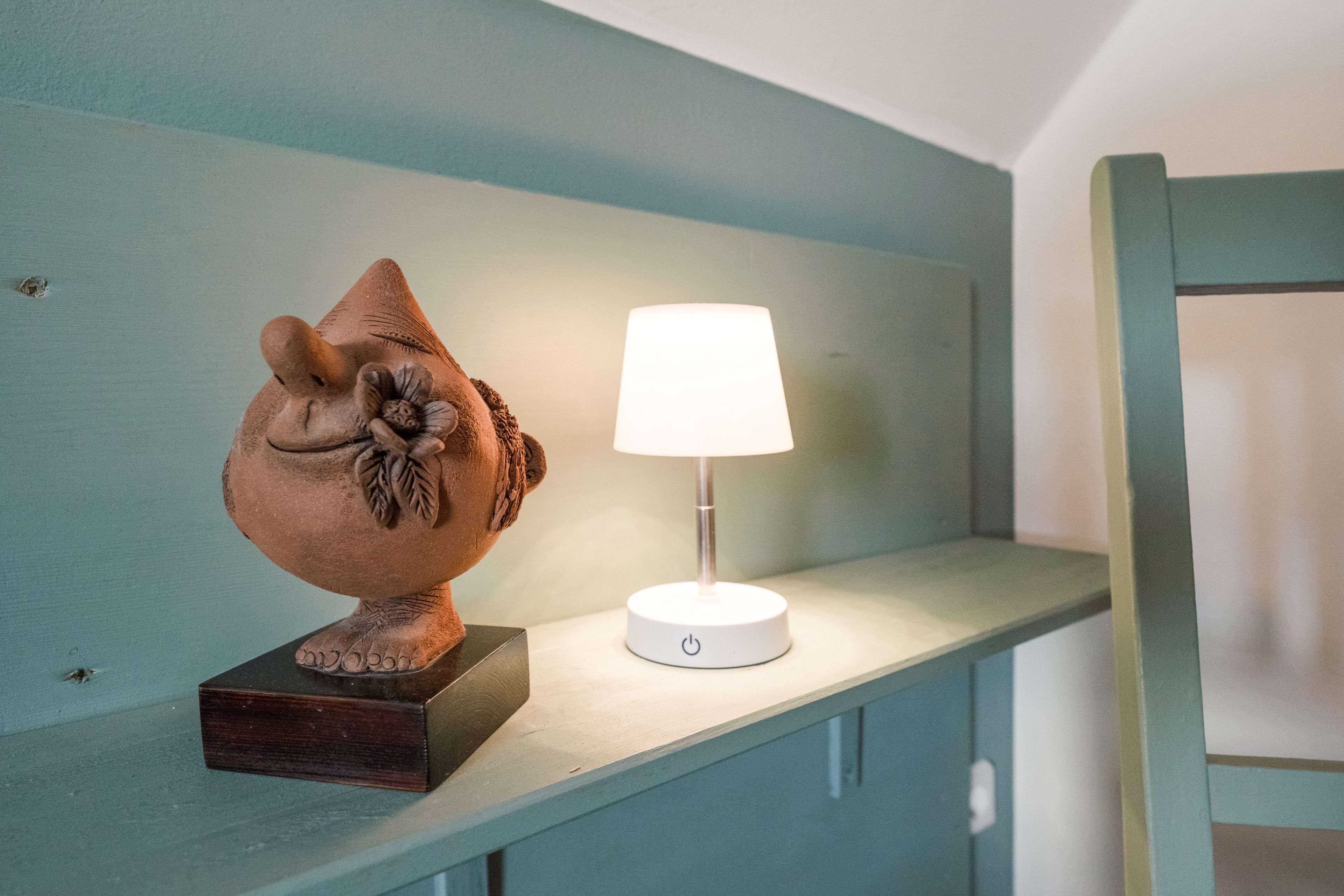 Eine Skulptur auf einem Regal neben einer Lampe.