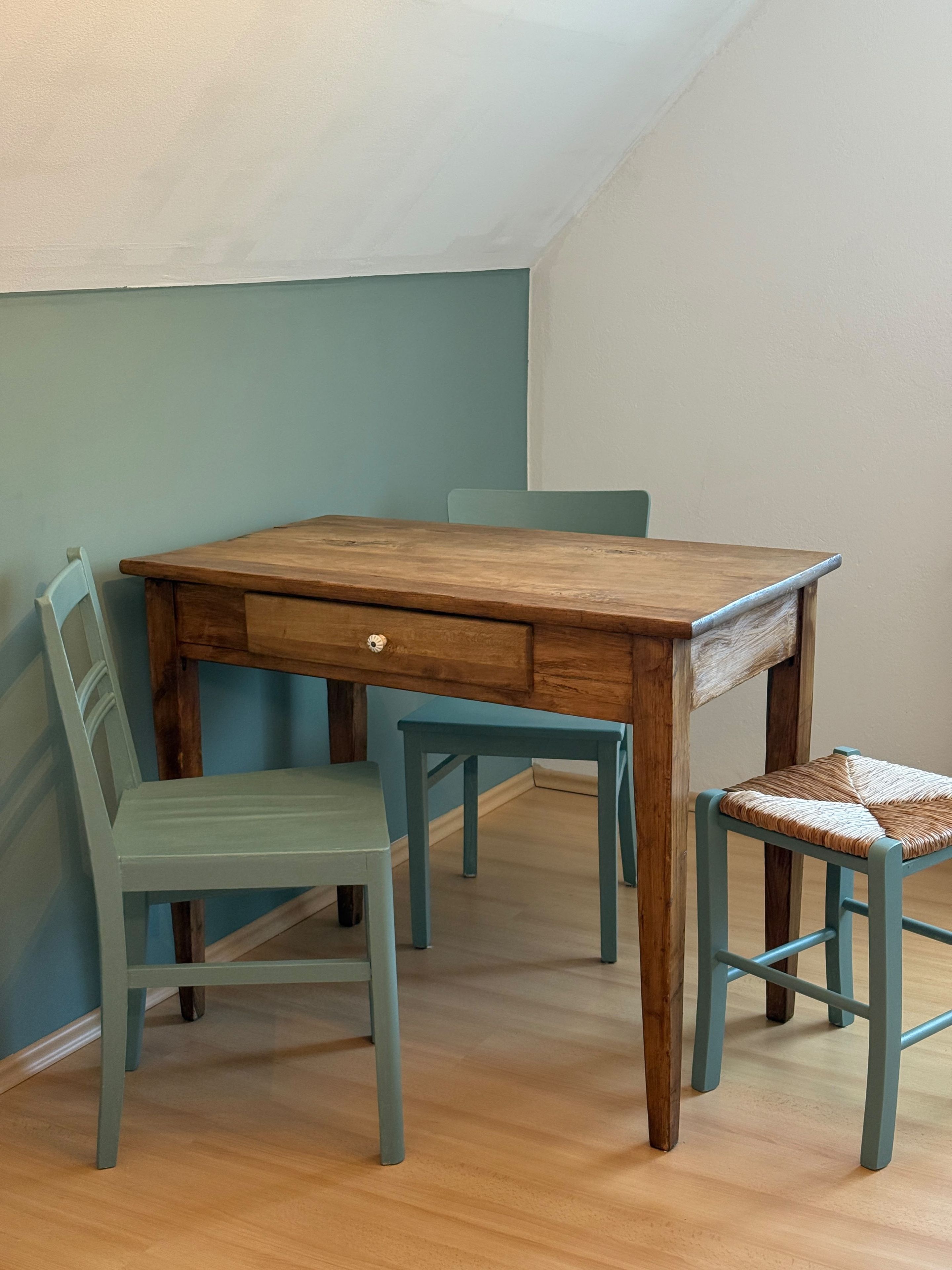 A dining table with four chairs, a drawer, and a wooden floor.