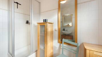Ein Badezimmer mit Dusche, Waschbecken, Spiegel und Schrank.