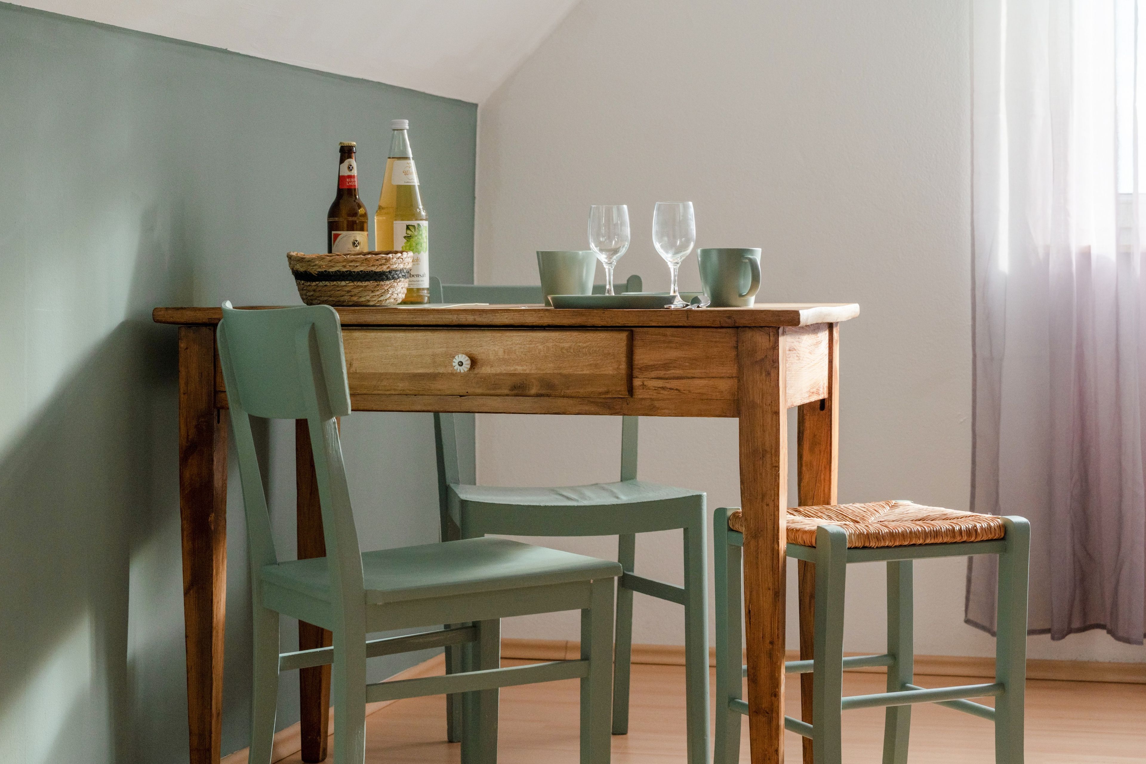 Una mesa de madera con una cesta tejida, dos botellas y dos vasos.