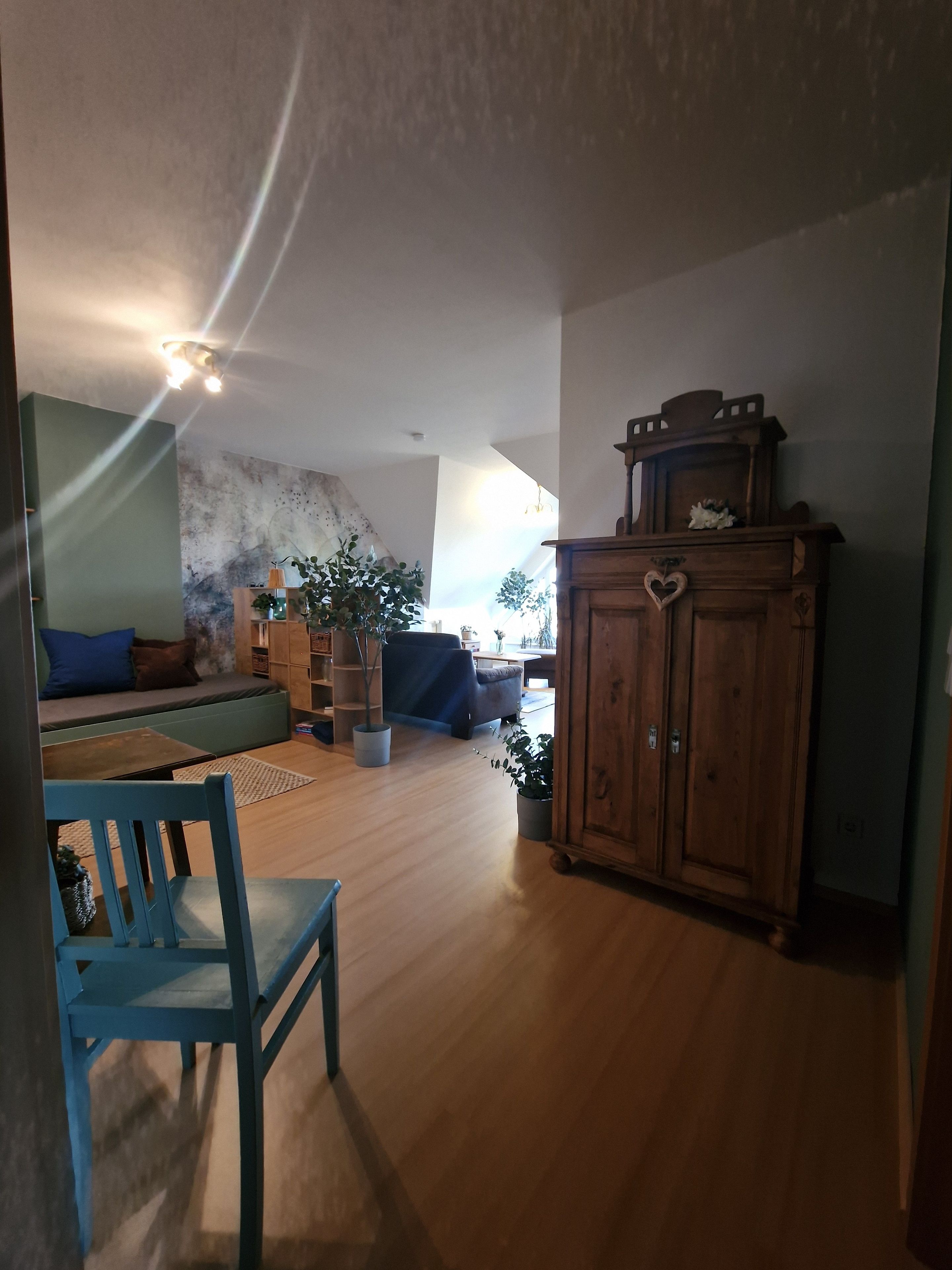 Ein Wohnzimmer mit einer Couch, einem Holzschrank und einem Essbereich mit einem Stuhl.