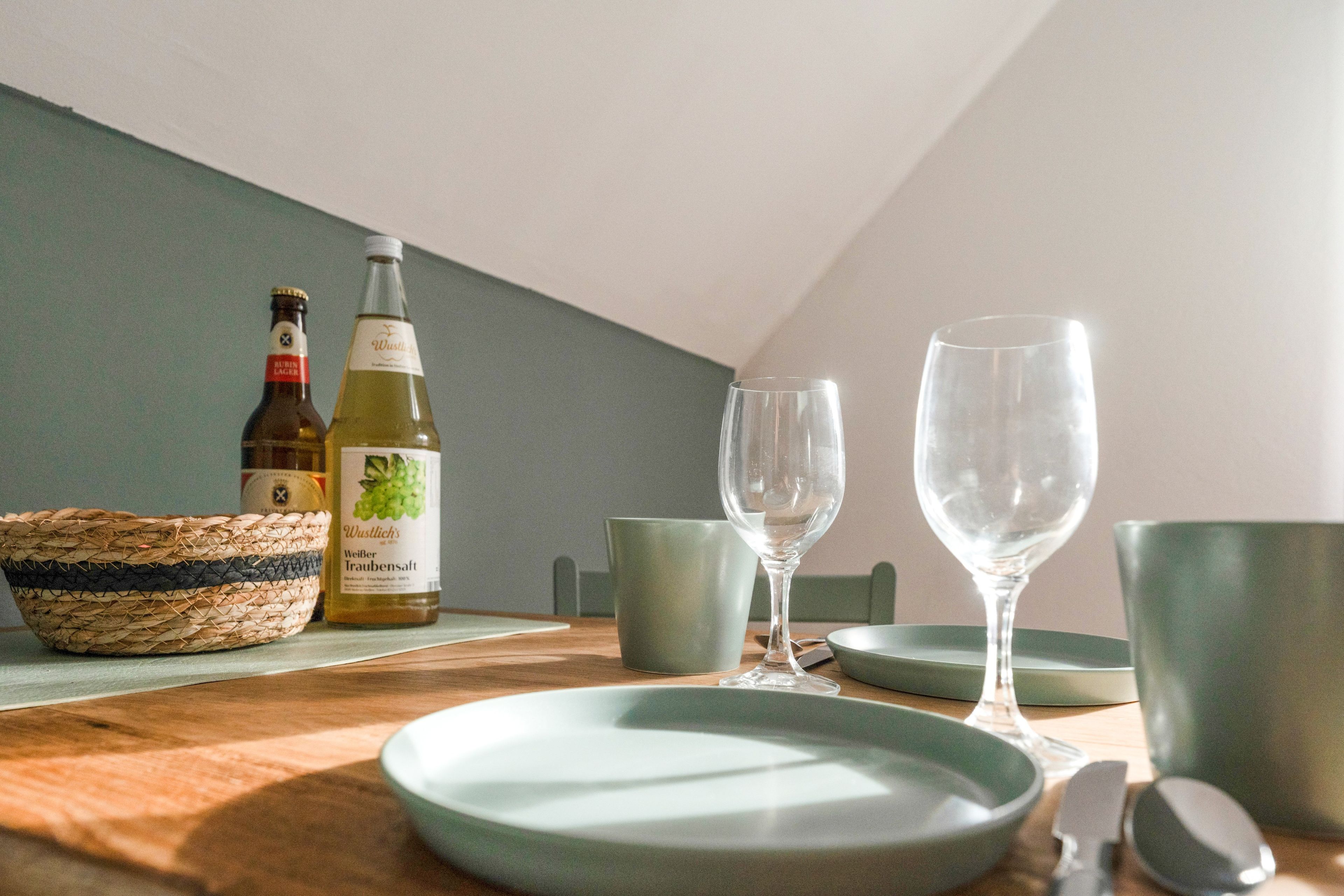 A dining table with a bottle of beer, a glass, and a bowl.