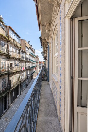 A narrow corridor with a metal railing, connecting two buildings with ornate facades and balconies. - Virginie Almada Apartment (Porto)