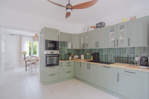 A modern kitchen with light green cabinets, a built-in oven, microwave, and coffee maker. - Villa Campbell - entre Biarritz et Bayonne (Anglet)