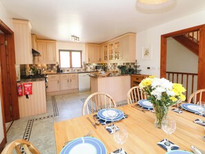 A dining area with a wooden table set for four, surrounded by chairs. - Stone Lily Cottage (Buxton)