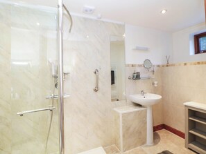 A bathroom with a glass-enclosed shower, a pedestal sink, and a mirror above it. - Stone Lily Cottage (Buxton)