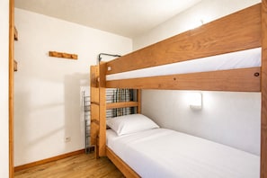 A bunk bed with a wooden frame, white bedding, and a wall-mounted light fixture. - DFJ Des Neiges - station de ski accessible à pied (Chamrousse)