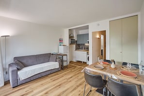 A compact living space with a sofa, dining table, chairs, a kitchenette, and a small kitchen area. - L'écrin d'Arcachon - proche des plages (Arcachon)