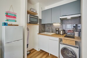 A compact kitchen with a refrigerator, microwave, sink, and a washing machine. - L'écrin d'Arcachon - proche des plages (Arcachon)