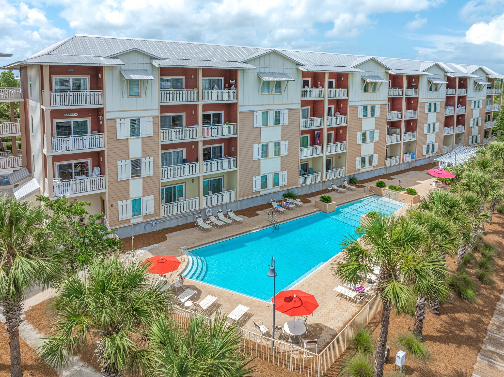 A multi-story hotel with balconies, a swimming pool, and outdoor seating areas.