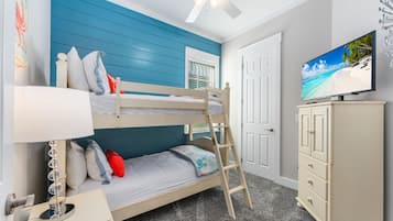 A bunk bed with a ladder, a television on a cabinet, and a ceiling fan.