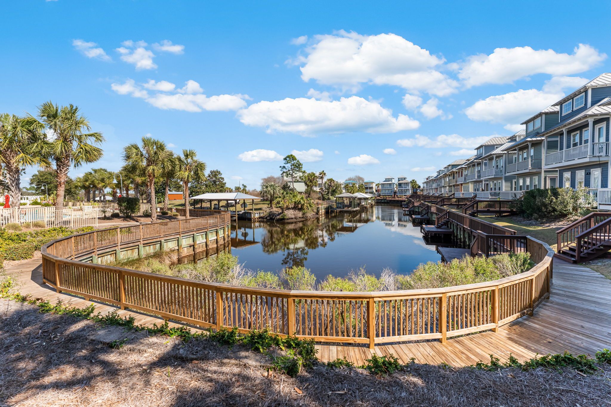 A waterfront property with a wooden deck, a calm lake, and a row of multi-story buildings.