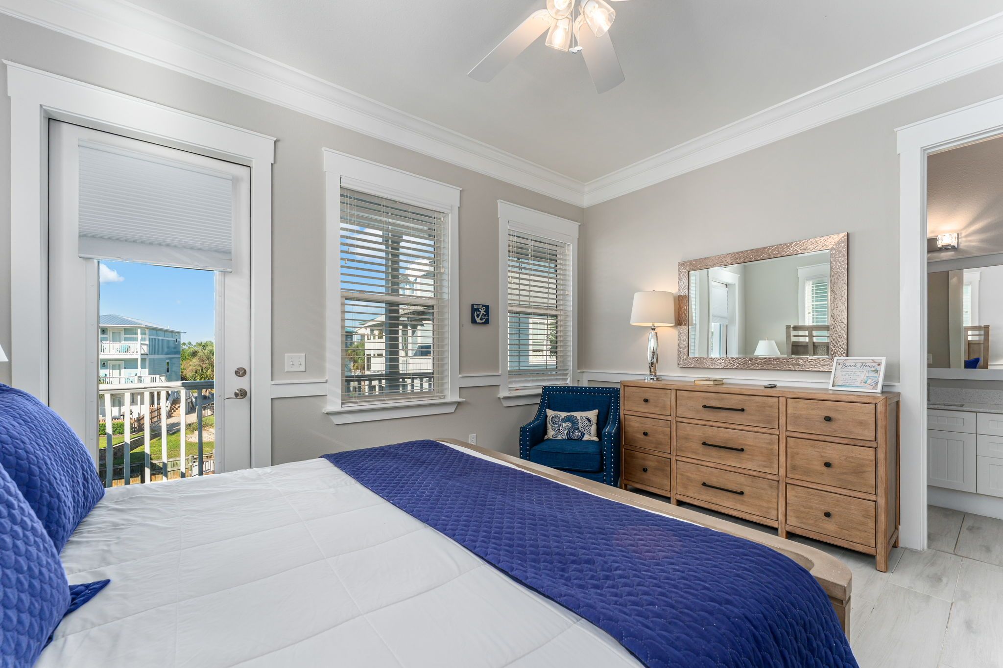 Une chambre à coucher avec un lit, une commode, un miroir et des fenêtres.
