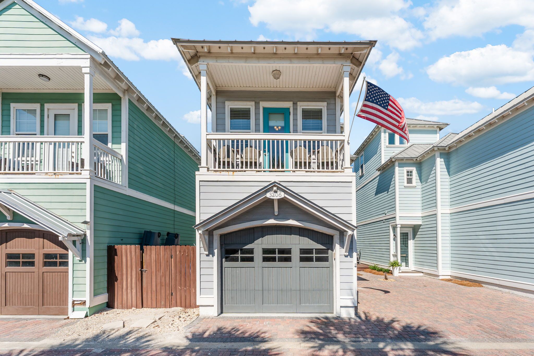 A two-story residential building with a garage, a balcony, and an American flag.