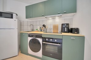 A compact kitchen with a washing machine, a coffee maker, and a toaster. - La Maison Petite Pause - plage à 150 m (Bray-Dunes)