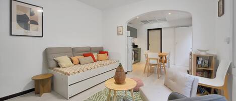 A modern living room with a sofa, a dining table, and a kitchen area in the background.