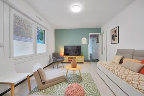 A modern living room with a sofa, a TV, a coffee table, and a chair. - La Maison Petite Pause - plage à 150 m (Bray-Dunes)